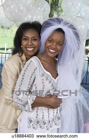 Stock Image - Mother embracing her daughter at bridal shower. Fotosearch