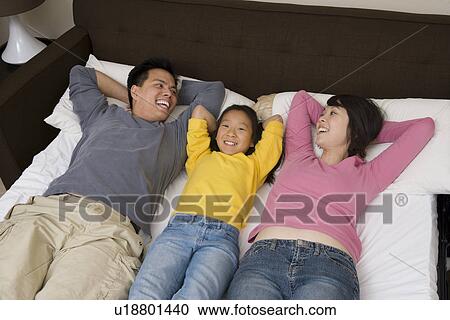 Mother, father and daughter lying down on bed and relaxing View Large Photo Image Stock Image - Mother, father and daughter lying down on bed and relaxing. Fotosearch