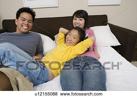 Mother, father and daughter lying down on bed and relaxing View Large Photo Image Stock Photo - Mother, father and daughter lying down on bed and relaxing. Fotosearch
