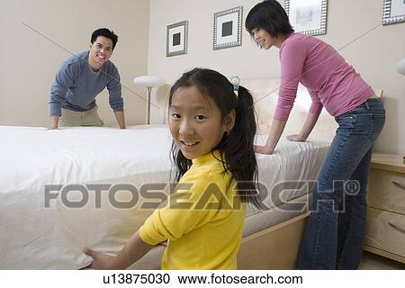 Mother, father and daughter making a bed together View Large Photo Image Stock Image - Mother, father and daughter making a bed together. Fotosearch