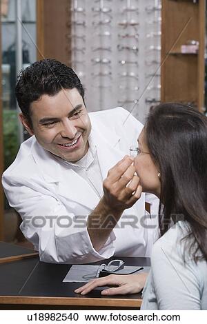 Stock Image - Optician helping customer. Fotosearch