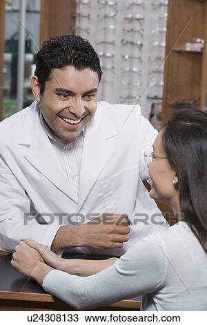 Stock Image - Optician helping customer. Fotosearch