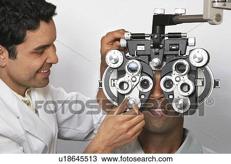 Stock Image - Optician performing eye test on patient. Fotosearch