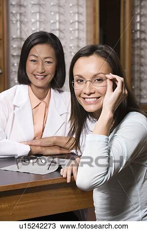 Stock Image - Optician with customer in store. Fotosearch