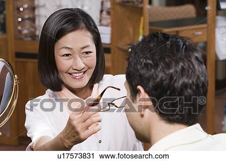 Stock Image - Optician with customer in store. Fotosearch
