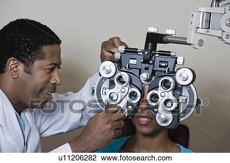 Stock Image - Optometrist examining patient's eyes. Fotosearch