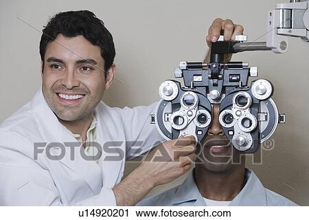 Stock Image - Optometrist examining patient's eyes. Fotosearch