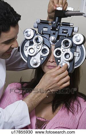 Stock Image - Optometrist examining patient's eyes. Fotosearch