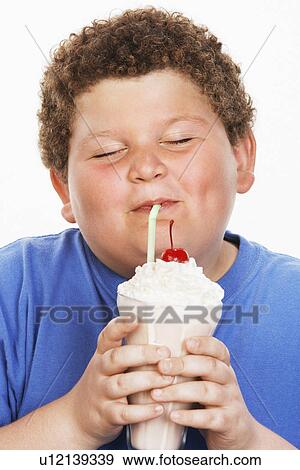 Stock Photo - Overweight boy (13-15) drinking milk shake, eyes closed, front view. Fotosearch