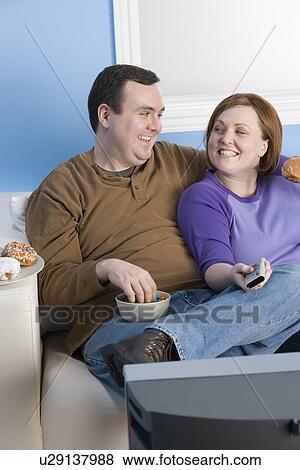 Overweight couple eating on sofa View Large Photo Image Stock Photo - Overweight couple eating on sofa. Fotosearch