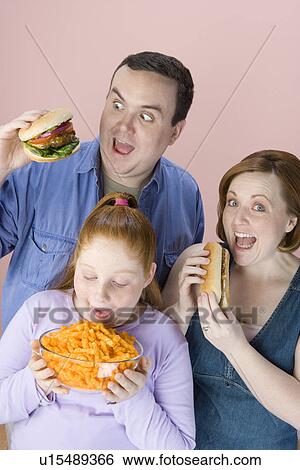 Stock Photograph - Overweight family holding unhealthy food. Fotosearch