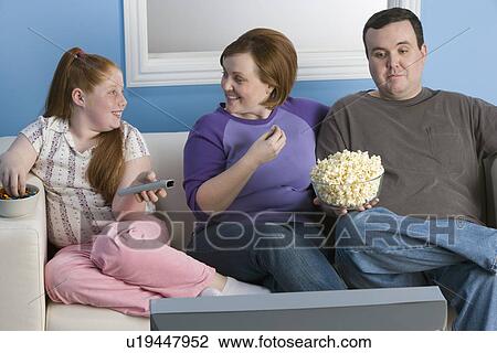 Overweight family watching television on sofa View Large Photo Image Stock Image - Overweight family watching television on sofa. Fotosearch