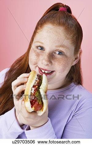 Stock Photograph - Overweight girl (13-15) Eating hot dog, portrait, close-up. Fotosearch
