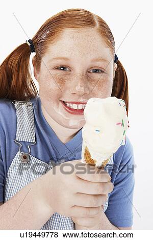 Overweight girl (13-15) smiling, cream on face, holding ice cream cone, portrait View Large Photo Image Stock Photo - Overweight girl (13-15) smiling, cream on face, holding ice cream cone, portrait. Fotosearch