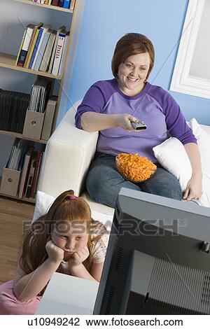 Stock Image - Overweight girl and mother watching television. Fotosearch
