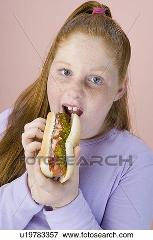 Stock Photo - Overweight girl eating hot dog, portrait. Fotosearch