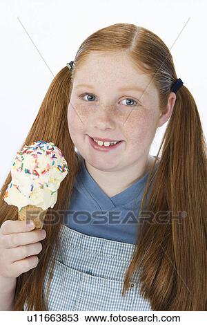 Stock Image - Overweight girl holding ice cream cone, portrait. Fotosearch