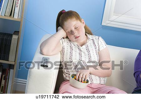 Stock Image - Overweight girl sleeping on sofa. Fotosearch