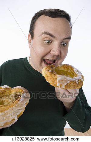 Stock Photography - Overweight mid-adult man eating pastry. Fotosearch