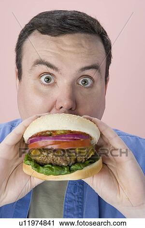 Overweight mid-adult man eating hamburger View Large Photo Image Stock Image - Overweight mid-adult man eating hamburger. Fotosearch