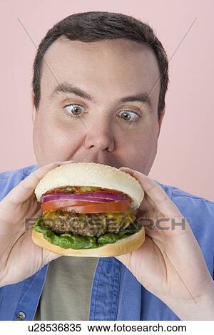 Overweight mid-adult man eating hamburger View Large Photo Image Stock Photography - Overweight mid-adult man eating hamburger. Fotosearch