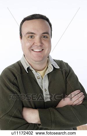 Stock Image - Overweight mid-adult man standing with arms crossed, portrait. Fotosearch