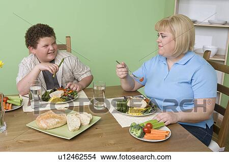 Picture - Overweight mother with overweight son having healthy meal. Fotosearch