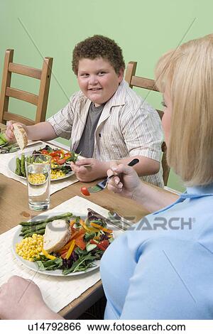 Stock Photograph - Overweight mother with overweight son having healthy meal. Fotosearch