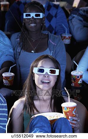 Stock Photo - People wearing 3-d glasses watching 3-D movie in theatre. Fotosearch