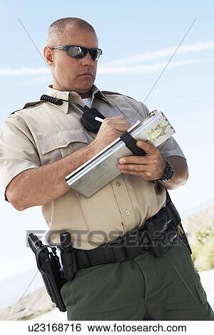 Stock Photograph - Police officer writing ticket, low angle view. Fotosearch