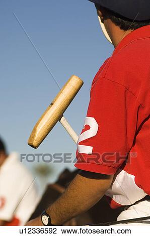 Stock Image - Polo player holding polo mallet, close-up, cropped. Fotosearch