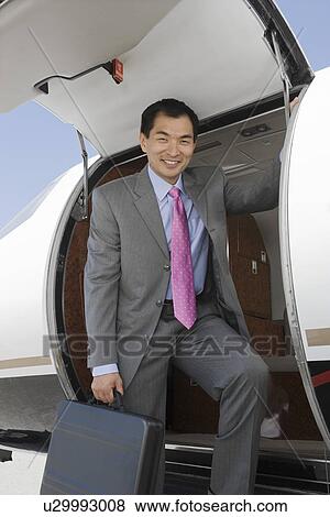 Stock Photo - Portrait of Asian businessman getting off private airplane.. Fotosearch