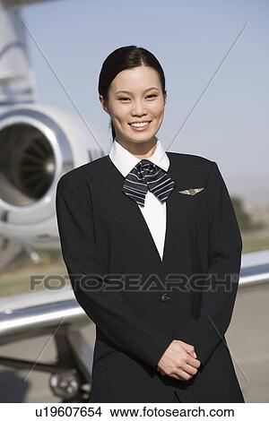 Portrait of Asian mid-adult flight attendant in front of airplane. View Large Photo Image Picture - Portrait of Asian mid-adult flight attendant in front of airplane.. Fotosearch