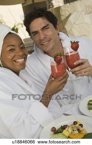 Stock Photograph - Portrait of couple in bathrobes, drinking at health spa. Fotosearch