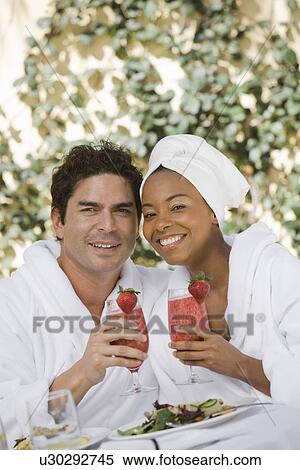 Stock Photography - Portrait of couple in bathrobes, drinking at health spa. Fotosearch