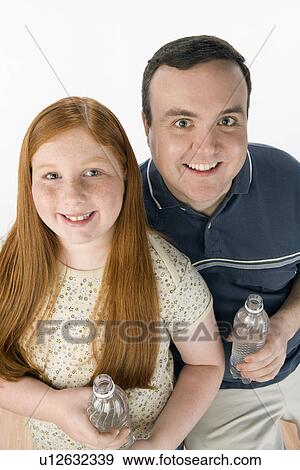 Stock Photo - Portrait of father and daughter holding bottles. Fotosearch