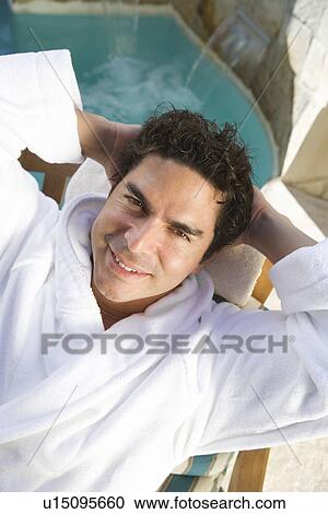 Stock Image - Portrait of man relaxing by swimming pool. Fotosearch