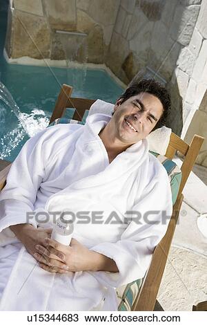 Stock Image - Portrait of man relaxing by swimming pool. Fotosearch