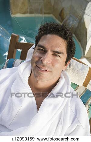 Stock Photo - Portrait of man relaxing by swimming pool. Fotosearch