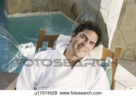 Stock Photo - Portrait of man relaxing by swimming pool. Fotosearch