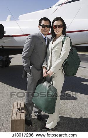 Portrait of mid-adult Asian business couple standing outside of private airplane. View Large Photo Image Stock Photograph - Portrait of mid-adult Asian business couple standing outside of private airplane.. Fotosearch