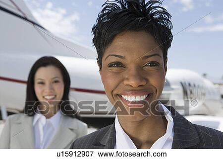 Stock Photo - Portrait of mid-adult businesswoman standing in front of private plane.. Fotosearch