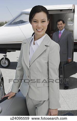 Portrait of mid-adult businesswoman standing in front of convertible, mid-adult businessman in background. View Large Photo Image Stock Photo - Portrait of mid-adult businesswoman standing in front of convertible, mid-adult businessman in background.. Fotosearch