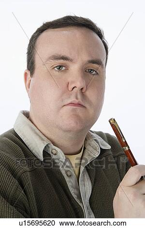 Stock Image - Portrait of mid-adult man holding pen. Fotosearch