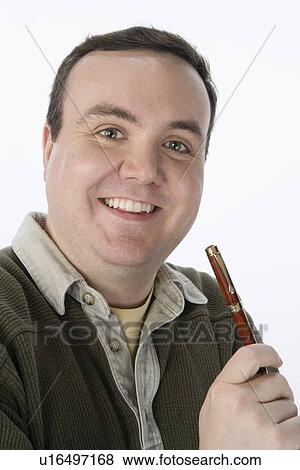 Stock Photo - Portrait of mid-adult man holding pen, smiling. Fotosearch