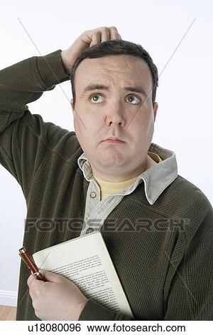 Stock Photograph - Portrait of mid-adult man holding pen and book, scratching his head. Fotosearch