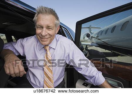 Stock Image - Portrait of senior businessman in front of car.. Fotosearch