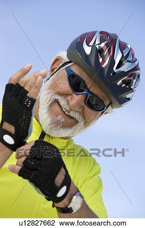 Stock Image - Portrait of Senior man adjusting cycling gloves. Fotosearch