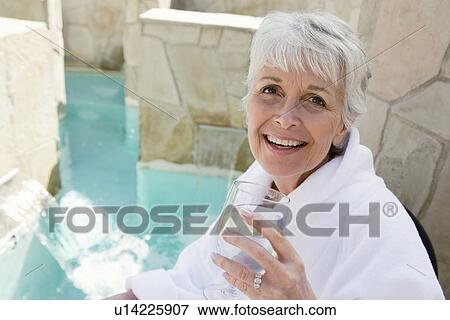 Stock Photo - Portrait of senior woman drinking by pool. Fotosearch