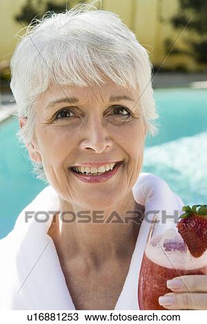 Stock Image - Portrait of senior woman holding strawberry cocktail. Fotosearch